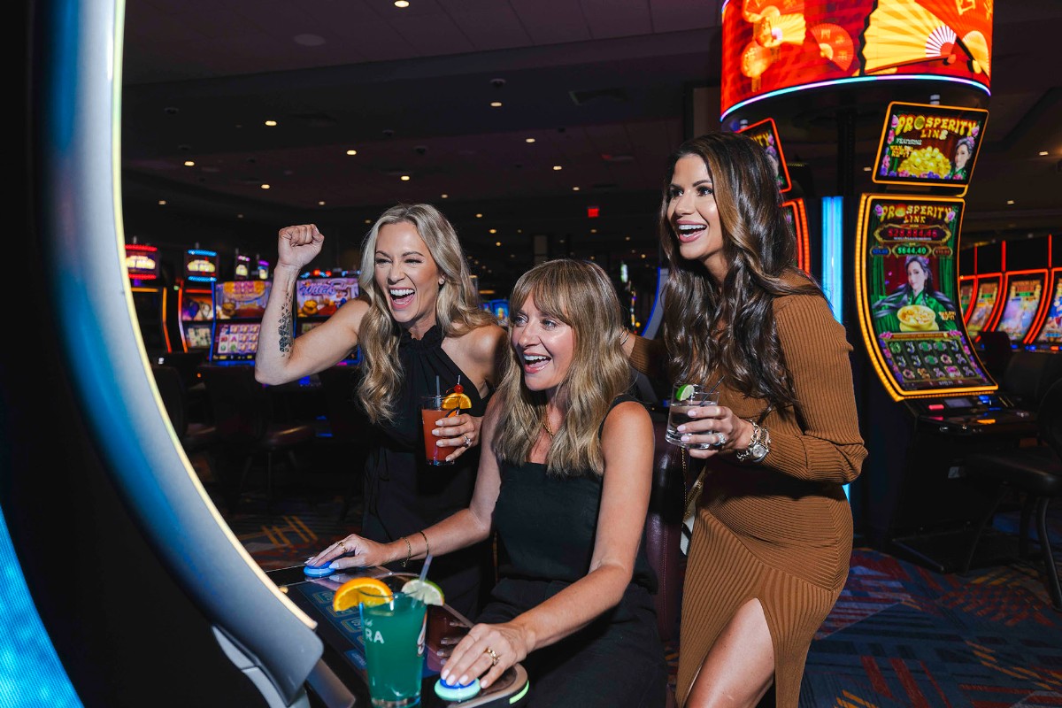 A group of stylishly dressed guests play the slot machines at Oaklawn Hot Springs