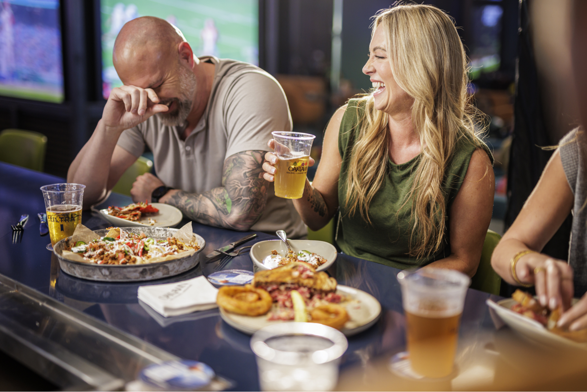 Laughing couple enjoys dinner and drinks at Oaklawn's Mainline Sports Bar.