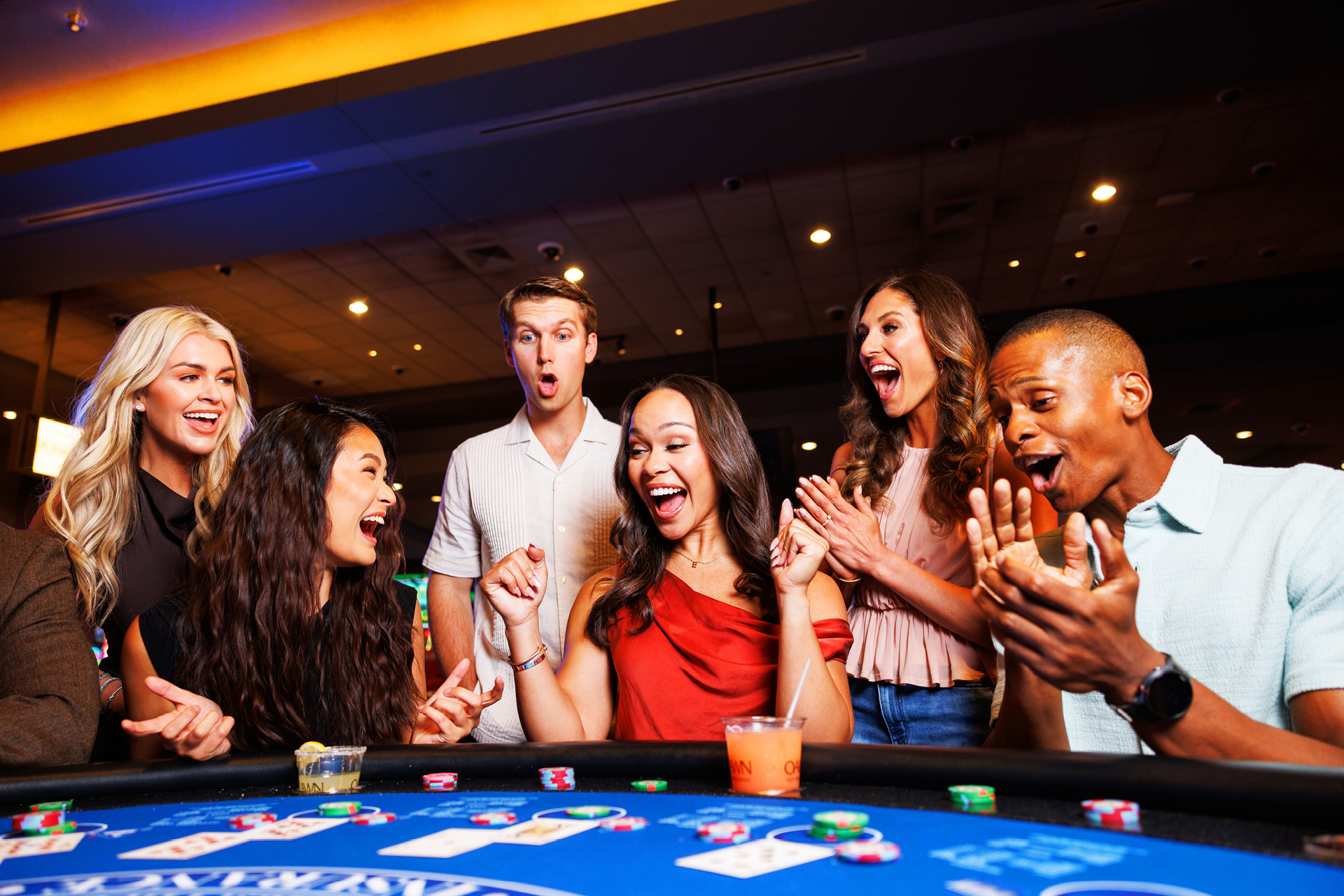 A group of patrons play at a full Black Jack table
