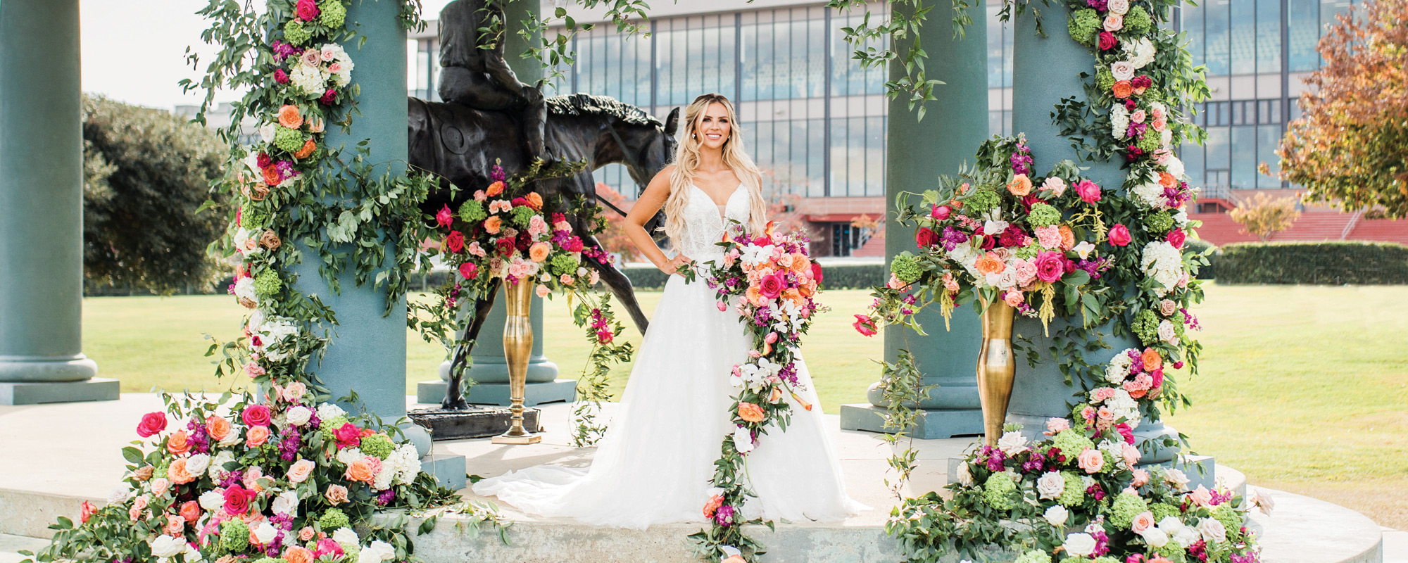 A beautiful bride surrounded by flowers poses in the infield at the Oaklawn Hot Springs racetrack